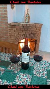 uma garrafa de vinho sentada numa mesa com dois copos de vinho em Latvia Chalés em Monte Verde