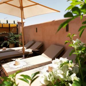 a group of tables with an umbrella and white flowers at Riad Miral in Marrakesh