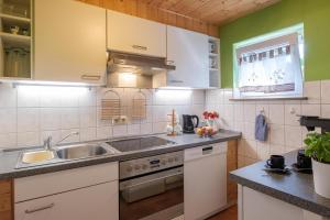 eine Küche mit weißen Schränken und einem Waschbecken in der Unterkunft Ferienwohnung Liebelt in Mitgenfeld , bayerische Rhön in Mitgenfeld