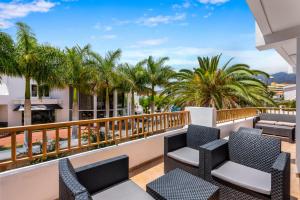 a balcony with chairs and palm trees at Luxury Apartaments in Costa Adeje, Los Geranois in Adeje