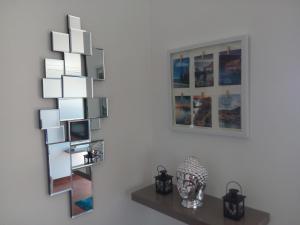 a wall with a mirror and a shelf with photos at Casa de Campo in Caniço