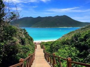 un camino de madera que conduce a una playa con el océano en Apartamento na Prainha, de um quarto!, en Arraial do Cabo