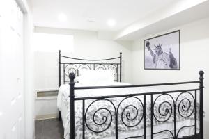 Una cama negra en un dormitorio blanco con una foto en la pared en Best EWR Airport Apt-Hot Tub-Free Parking en Hillside