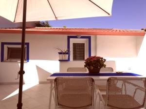a table with chairs and an umbrella on a patio at La Porta Blu in Teulada