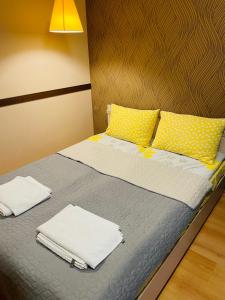 a bed with yellow pillows and towels on it at Studio Kris Villa Park in Borovets