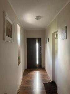 korytarz z czarnymi drzwiami i drewnianą podłogą w obiekcie mieszkanie na osiedlu siedemsetlecia w Uniejowie