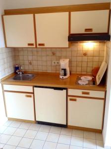 a kitchen with white cabinets and a sink at Appartementhaus Panny in Bad Füssing