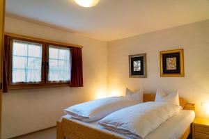 a bedroom with a bed with white pillows and a window at Kulmwiesli in Arosa