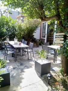 un patio con mesas y sillas en un jardín en Coconut Beach apartments, en Zandvoort