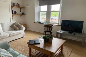 a living room with a couch and a table and a tv at Harbourside Apartment in Eyemouth
