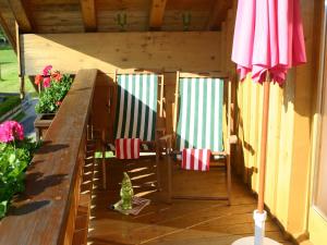 una terraza con 2 sillas y una sombrilla en Casa Claudia - die schöne 4-Sterne-Fewo - im Sommer Bergbahntickets inclusive, en Oberstdorf
