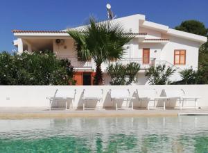 a house with chairs and a swimming pool at Il Volo Dei Gabbiani in Scopello