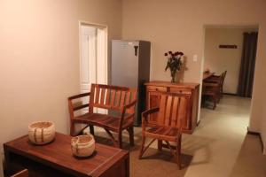 du Repos (Lovely & Relaxing 2-Bedroom Unit with Patio) في جلوسوب: غرفة معيشة فيها كراسي وطاولة وثلاجة