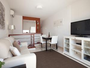 sala de estar con sofá blanco y TV en Blaumar, en Sitges