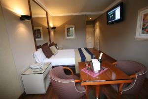 Motel Aeropuerto في فيغو: غرفة فندقية بسرير وطاولة وكراسي