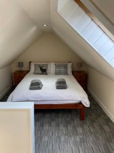 a bedroom with a white bed in a attic at 1-2 Dialknowe Holiday Cottage - Wanlockhead in Wanlockhead