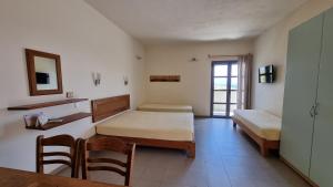 a room with two beds and a table and chairs at Domatia me Thea in Elafonisos