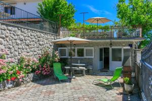 a stone house with a patio with chairs and an umbrella at Apartment Jurja in Ledenice