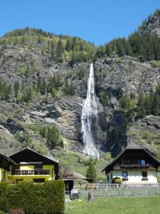 a waterfall on the side of a mountain with houses at Haus Harmonie in Millstatt