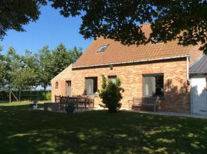 a brick house with two benches in a yard at Valkenhof in Veurne