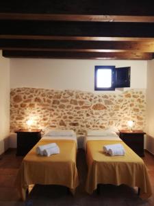 two beds in a room with a stone wall at Il Volo Dei Gabbiani in Scopello
