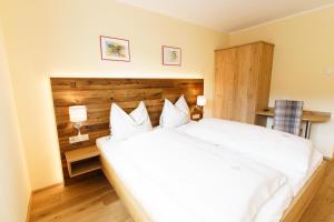 a bedroom with a large white bed with two lamps at Hotel Die Metzgerstubn in Sankt Michael im Lungau