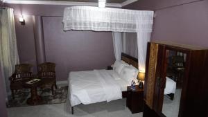 a bedroom with a white bed and two chairs at Jakicha Motel in Dar es Salaam