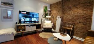 a living room with a brick wall and a tv at LUXE BROOKLYN Getaway in Brooklyn