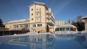 ein Gebäude im Schnee mit einem Swimmingpool in der Unterkunft Hotel Almesberger in Aigen im Mühlkreis