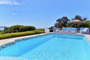 een groot zwembad met stoelen bij VILLA JUCANOS - Vue mer panoramique Golfe de St-Tropez in Cavalaire-sur-Mer