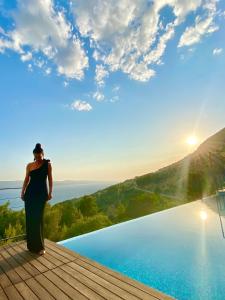 een vrouw op een terras naast een zwembad bij Villa FORTE-Exclusive location with fantastic seaview & infinity pool - up to 8 Pax in Mimice