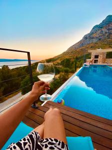 een persoon met een glas wijn naast een zwembad bij Villa FORTE-Exclusive location with fantastic seaview & infinity pool - up to 8 Pax in Mimice