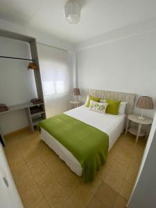 ein Schlafzimmer mit einem großen weißen Bett mit grüner Bettwäsche in der Unterkunft Blue Beach House ATICO CON TERRAZA in Málaga