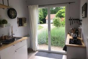 una cocina con una puerta corredera de cristal que da a un patio en Les Genêts, en Fontaine-sous-Jouy