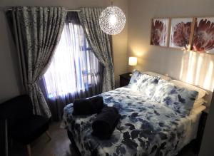 a bedroom with a bed with pillows and a window at Locust Retreat Immaculate 2bedroom cottage in Marloth Park