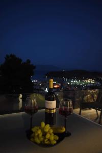 a bottle of wine and two wine glasses on a table at Nera's view in Ancient Epidauros