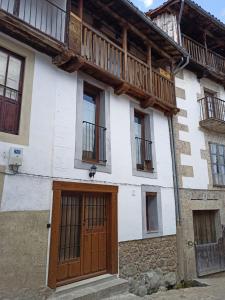 Cette maison dispose d'une porte en bois et d'un balcon. dans l'établissement La Herrerita, à Candelario