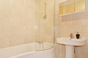 y baño con lavamanos, bañera y lavamanos. en Beautiful 6 Bedroom with spacious Lounge & Rooms Free parking, en Erith