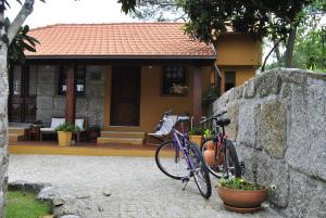 Una bicicleta púrpura estacionada contra una pared de piedra frente a una casa en Leiras do Seixo - Casa dos Tinos, en Amarante