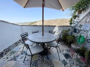 un patio con mesa, sillas y sombrilla en Casa Vacacional Alcazabilla en Antequera