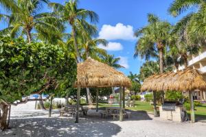 a park with tables and straw umbrellas and palm trees at Best Western Plus Beach Resort in Fort Myers Beach