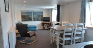 sala de estar con mesa, sillas y TV en Relax in a 1 Bedroom Apartment near a country Pub, en Eyemouth