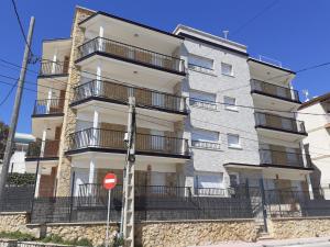un edificio blanco alto con balcones y un letrero de la calle en Apartamentos Dins Mar Apto. 1 en Torredembarra