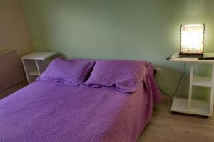 uma cama com um cobertor roxo num quarto em Departamento frente al mar em Santa Teresita