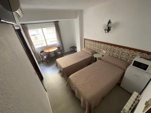 1 dormitorio pequeño con 2 camas y mesa en Pensión Eurosol, en Granada