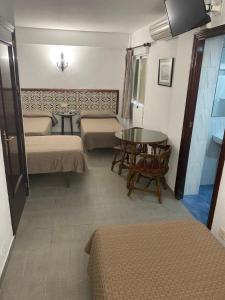 Pokój z dwoma łóżkami i stołem oraz tableasteryasteryasteryasteryastery w obiekcie Pensión Eurosol w Grenadzie