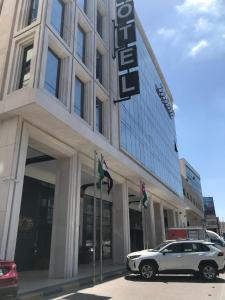 een witte auto geparkeerd voor een gebouw bij Lilac Hotel - Amman in Amman