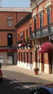 eine Stadtstraße mit einem Gebäude mit Balkonen und Blumen in der Unterkunft Los Balcones del Camino in Sahagún