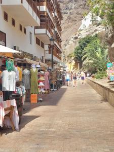 Un gruppo di persone che camminano per strada con un mercato di Los Gigantes apartment 113, 1 bedroom ad Acantilado de los Gigantes