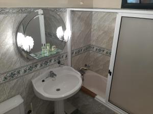 een badkamer met een wastafel, een spiegel en een bad bij Casa do Terço in Câmara de Lobos